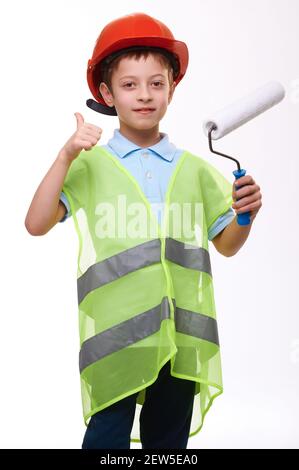 Ragazzo in costruzione giubbotto verde tenendo rullo di vernice mostra il pollice gesto verso l'alto su sfondo bianco isolato Foto Stock