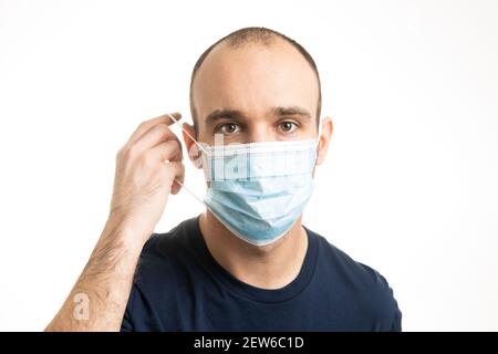 Un maschio bianco caucasico che indossa una maglietta blu e indossa una maschera chirurgica blu. Foto Stock