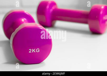 Due manubri rosa gommati da due chilogrammo isolati su sfondo bianco. Vista dall'alto. Piatto. Il concetto di uno stile di vita sano e sport, fitne Foto Stock
