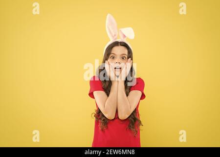 buona infanzia. bambini sorpresi festeggiano la festa di pasqua. tradizione di festa di primavera. scolaretta divertirsi. festa tradizionale. Costume del coniglietto di Pasqua. Ragazza piccola divertente nelle orecchie del coniglio. Foto Stock