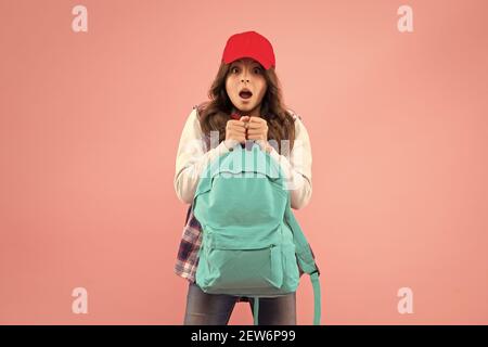 Non è così. Trasporto di oggetti in zaino. Scopri come montare correttamente lo zaino. Zaino per bambini alla moda ragazza. Utile accessorio di moda. Scolaretta rossa cappuccio capelli lunghi con zaino scuola. Foto Stock