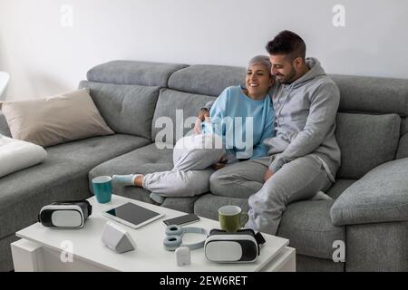 La giovane coppia felice è sdraiata su un nuovo lettino nel soggiorno e riposarsi. Luminoso appartamento moderno con arredi eleganti Foto Stock