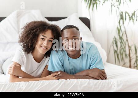 Giovane coppia sorridente carino insieme a letto, blogger popolari casa durante covid-19 blocco Foto Stock