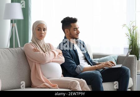 Annoiata Madonna musulmana incinta offesa a suo marito Busy con Computer portatile Foto Stock