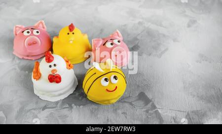 Torta sotto forma di animali. Il soufflé fatto in casa in glassa è decorato sotto forma di facce animali. Maiali, polli e api sotto forma di cak per bambini Foto Stock