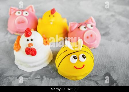 Torta sotto forma di animali. Il soufflé fatto in casa in glassa è decorato sotto forma di facce animali. Maiali, polli e api sotto forma di cak per bambini Foto Stock