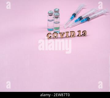 Prevenzione delle malattie stagionali. Fiale mediche e siringhe su sfondo rosa. Vaccinazione contro covid-19. Foto Stock