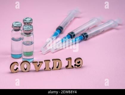 Prevenzione delle malattie stagionali. Fiale mediche e siringhe su sfondo rosa. Vaccinazione contro covid-19. Foto Stock