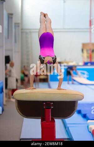 Una giovane ragazza in abbigliamento sportivo esegue un salto su un proiettile. Ginnastica ritmica, allenamento in sala. Foto Stock