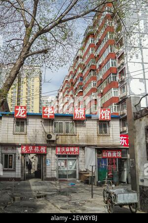 Pechino, Cina - 25 aprile 2010: Vista sul cortile sul commercio di cibo trashy sul retro di edifici di appartamenti in pietra rossa e gialla con segnaletica mandarina e. Foto Stock