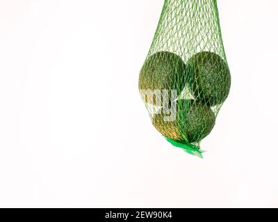 Avocado in una rete verde isolato e sospeso in aria con sfondo bianco in studio Foto Stock