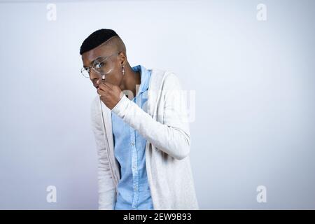 Giovane bell'uomo afro-americano che indossa abiti casual sorpreso nel look attraverso una lente di ingrandimento Foto Stock