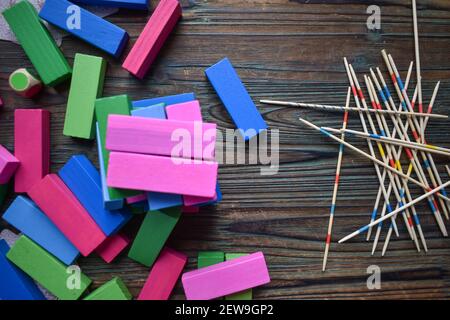 Una vista dall'alto di colorati blocchi di legno rettangolari e Mikado bastoni di raccolta sul tavolo di legno Foto Stock
