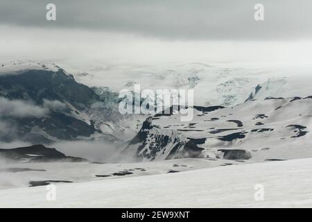 Paesaggio bianco nevoso e foggoso a Fimmvarduhals sentiero escursionistico, un ghiacciaio sullo sfondo, Islanda Foto Stock