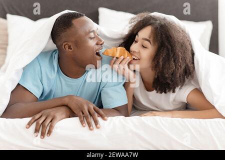 Colazione romantica a letto, luna di miele e divertimento insieme in una camera d'albergo accogliente Foto Stock