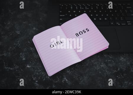 Concetto di pari opportunità, testo di Girl Boss sulla parte superiore del notebook rosa sulla tastiera del notebook su sfondo nero Foto Stock