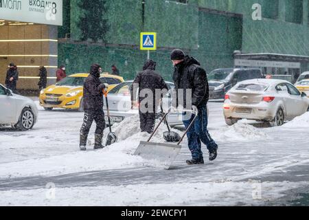 Mosca. Russia. 12 febbraio 2021. Un addetto alla pubblica utilità rimuove la neve con uno scraper su una strada cittadina durante una nevicata in una giornata invernale. labo fisico duro Foto Stock