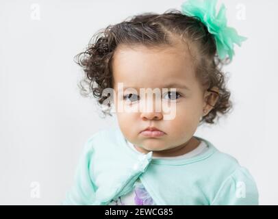 Una bambina con un'espressione facciale seria, che si pouda. Foto Stock