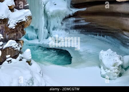 Un'immagine orizzontale dell'Athabasca cade in inverno con le cicale congelate aggrappate alle pareti del canyon roccioso nel Jasper National Park in Alberta Canada. Foto Stock