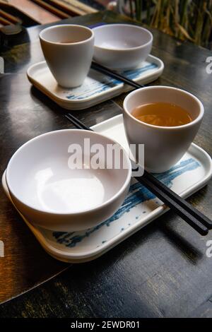 Due set di stoviglie in stile cinese sul tavolo da pranzo, ciotola di riso, chopsticks e teacup Foto Stock