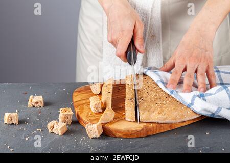 Una chef donna sta affettando pane turco piatto appena sfornato, conosciuto come pide o pita, su un tagliere di legno. Il pane integrale pita è rotondo wit Foto Stock