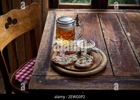 Dall'alto di deliziosi antipasti di pezzetti di pane di segale con soffici e fette di sale vicino a una pinta di bevanda alcolica su tavolo rustico Foto Stock