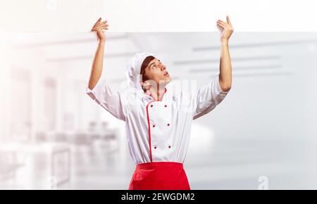 Giovane chef maschile con un cartello bianco vuoto Foto Stock