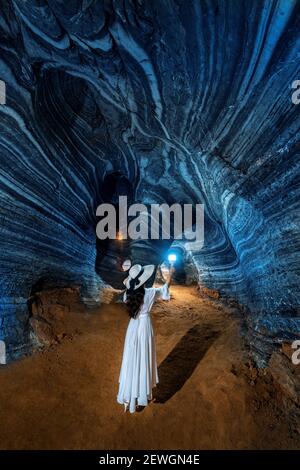 Bella ragazza in abito bianco che cammina nella grotta blu, Thailandia. Foto Stock