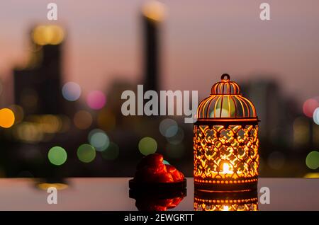 Lanterna d'oro e datteri frutta con cielo all'alba e città bokeh sfondo chiaro per la festa musulmana del mese santo di Ramadan Kareem. Foto Stock
