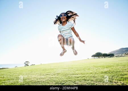 Giovane ragazza mista da corsa con lunghi capelli ricci che salgono dentro l'aria Foto Stock