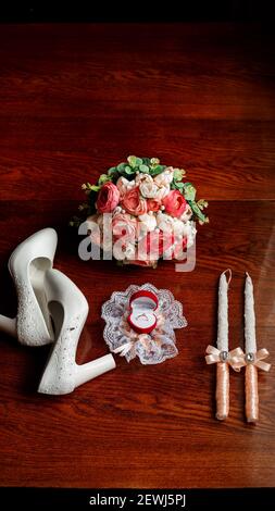 Mattina della sposa. Bouquet nuziale. Candele di nozze nella chiesa. Anelli di nozze in una scatola rossa. Scarpe bianche della sposa. Garter sulla gamba del br Foto Stock