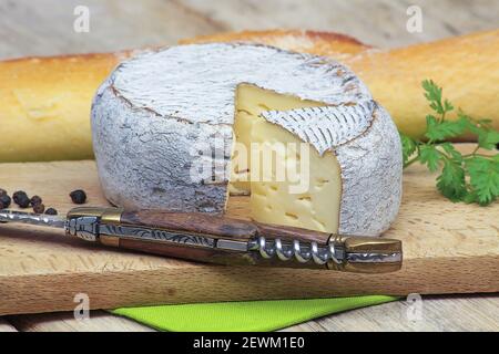 Formaggio Tomme de Savoie su un tagliere Foto Stock