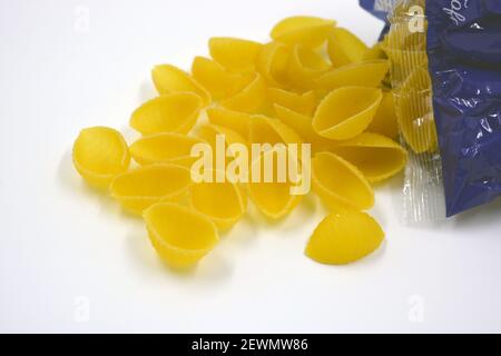 Vermicelli italiani gialli secchi, pasta fatta da conchiglie Wwkushi di varietà a grani solidi si trovano su uno sfondo bianco. Foto Stock