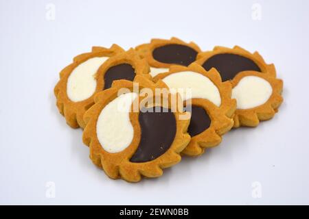 Biscotto di sicurezza sotto forma di sole con stucco bianco e cioccolato, dolce sotto forma di due gocce poste su fondo bianco. Foto Stock