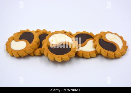 Biscotto di sicurezza sotto forma di sole con stucco bianco e cioccolato, dolce sotto forma di due gocce poste su fondo bianco. Foto Stock