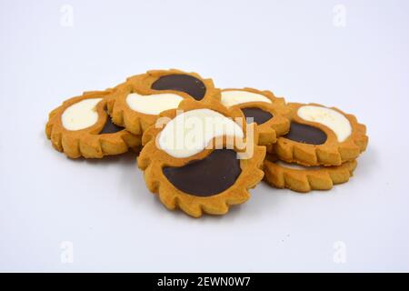 Biscotto di sicurezza sotto forma di sole con stucco bianco e cioccolato, dolce sotto forma di due gocce poste su fondo bianco. Foto Stock