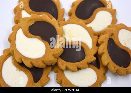 Biscotto di sicurezza sotto forma di sole con stucco bianco e cioccolato, dolce sotto forma di due gocce poste su fondo bianco. Foto Stock