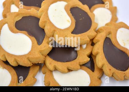 Biscotto di sicurezza sotto forma di sole con stucco bianco e cioccolato, dolce sotto forma di due gocce poste su fondo bianco. Foto Stock