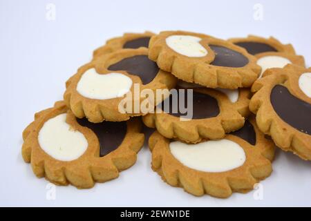 Biscotto di sicurezza sotto forma di sole con stucco bianco e cioccolato, dolce sotto forma di due gocce poste su fondo bianco. Foto Stock