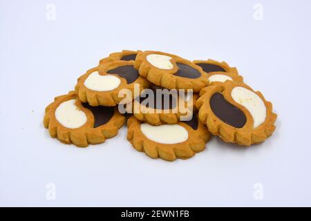 Biscotto di sicurezza sotto forma di sole con stucco bianco e cioccolato, dolce sotto forma di due gocce poste su fondo bianco. Foto Stock