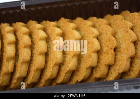 Deliziosi biscotti sabbiosi con bordi taglienti e cioccolato e riempitivo bianco investiti in confezioni marrone. Foto Stock