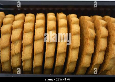 Deliziosi biscotti sabbiosi con bordi taglienti e cioccolato e riempitivo bianco investiti in confezioni marrone. Foto Stock