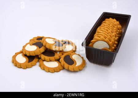 Deliziosi biscotti sabbiosi con bordi taglienti e cioccolato e riempitivo bianco investiti in confezioni marrone. Foto Stock