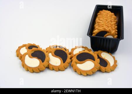 Deliziosi biscotti sabbiosi con bordi taglienti e cioccolato e riempitivo bianco investiti in confezioni marrone. Foto Stock