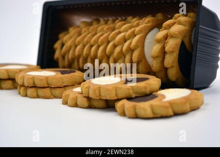 Deliziosi biscotti sabbiosi con bordi taglienti e cioccolato e riempitivo bianco investiti in confezioni marrone. Foto Stock