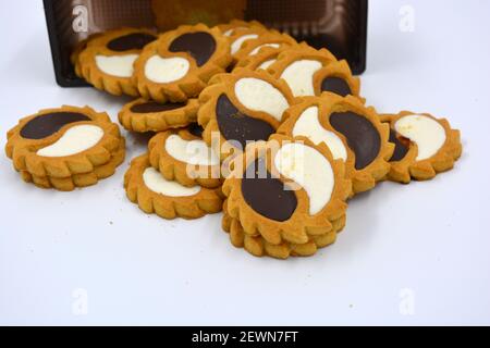 Deliziosi biscotti sabbiosi con bordi taglienti e cioccolato e riempitivo bianco investiti in confezioni marrone. Foto Stock