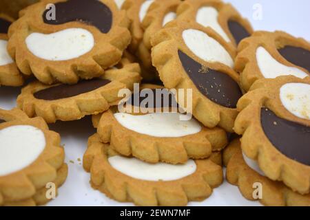 Biscotto di sicurezza sotto forma di sole con stucco bianco e cioccolato, dolce sotto forma di due gocce poste su fondo bianco. Foto Stock