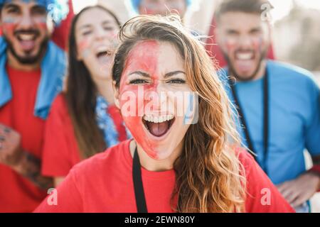 I fan di sport pazzi gridano mentre sostengono la loro squadra - Focus sulla ragazza centrale Foto Stock