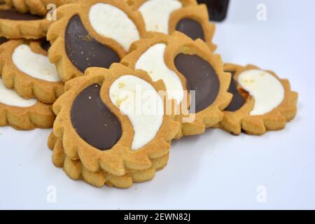 Biscotto di sicurezza sotto forma di sole con stucco bianco e cioccolato, dolce sotto forma di due gocce poste su fondo bianco. Foto Stock