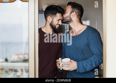 Coppia maschile gay che ha momento tenero mentre lavando i piatti all'interno cucina domestica - fuoco sui volti Foto Stock